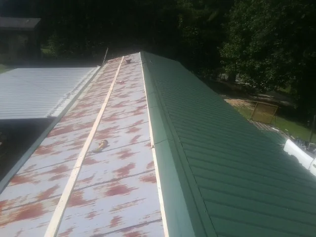 Old rusted panels beside newly installed green metal roofing — Wind Damage Roof Repair by Roofing Brothers in Livermore