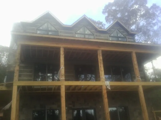 Dormers and porch framing on a large log home under construction — Roof Coating work by our crew in Livermore